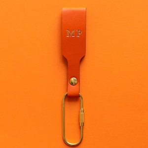 Orangener Schlüsselanhänger mit goldener Personalisierung und Messing-Karabiner