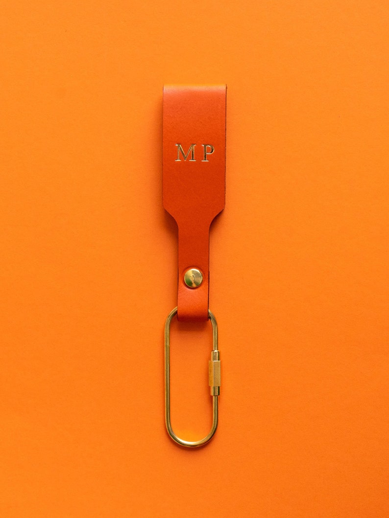 Orangener Schlüsselanhänger mit goldener Personalisierung und Messing-Karabiner