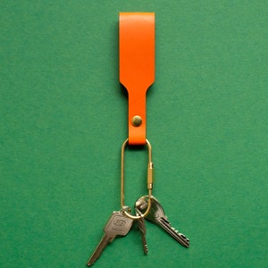 Orangener Schlüsselanhänger mit Messing-Karabiner und Schlüsseln