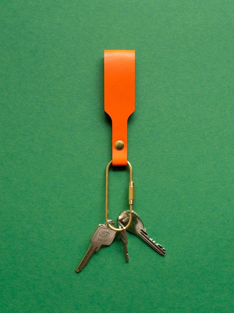 Orangener Schlüsselanhänger mit Messing-Karabiner und Schlüsseln