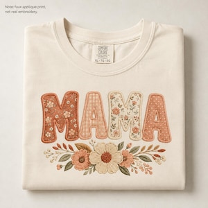 May include: Cream-colored sweatshirt with the word "MAMA" in a floral and patterned applique design. The letters are in shades of orange, peach, and cream, with a floral arrangement at the bottom. The tag reads "COMFORT COLORS XL-TG-EG".