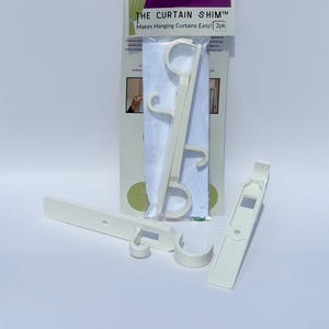 May include: Off-white curtain hanging tools, including two shims and a package with the text "THE CURTAIN SHIM™ Makes Hanging Curtains Easy!" The tools are designed to simplify the process of hanging curtains. The package says "2pk".
