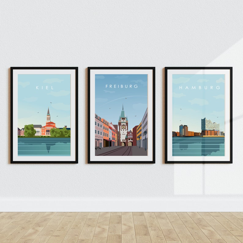 Op de afbeelding: Drie ingelijste stadsgezichten met de namen Kiel, Freiburg en Hamburg gedrukt bovenaan elk frame. De afbeeldingen zijn in een minimalistische stijl met een blauwe lucht en water.