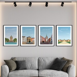 K&ouml;nnte beinhalten: Vier gerahmte Stadtansichten mit den Namen "Mannheim", "Aachen", "Freiburg" und "M&uuml;nster" oben auf jedem Rahmen. Die Bilder sind im minimalistischen Stil mit blauem Himmel und wei&szlig;en Wolken gehalten.