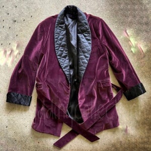 May include: A purple velvet robe with a black quilted lining and a black velvet tie. The robe has long sleeves and a shawl collar.