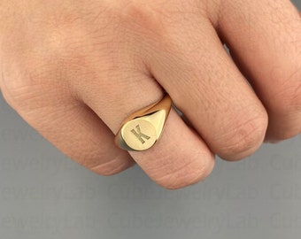 May include: A gold signet ring with the letter "K" engraved on the oval face.