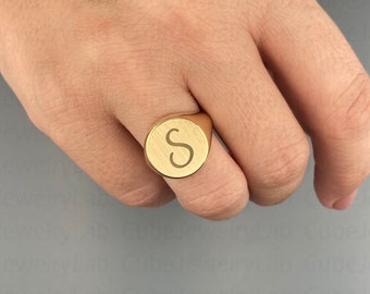 May include: A gold signet ring with the letter "S" engraved on the face.