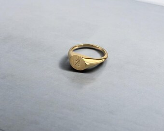 May include: A gold signet ring with the letter "A" engraved on the face.