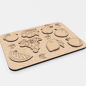 Puede incluir: Una tabla de madera con formas recortadas de varias frutas, incluyendo una sand&iacute;a, uvas, un lim&oacute;n, una pera, una manzana y una granada.