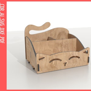 May include: A wooden organizer shaped like a cat's face with a compartment for storing items. The organizer has a light brown wood finish and a black outline.