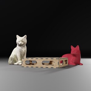 Puede incluir: Una figurita de gato de cer&aacute;mica blanca sentada junto a una figurita de zorro de cer&aacute;mica roja. Ambas figuritas est&aacute;n sobre una plataforma de madera con un dise&ntilde;o de corte.