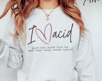 May include: A gray sweatshirt with the text "I ♥ acid" in black and pink. The text "glycolic, lactic, ascorbic, ferulic, kojic, azelaic, linoleic, salicylic, mandelic, hyaluronic" is printed in black below the main text.
