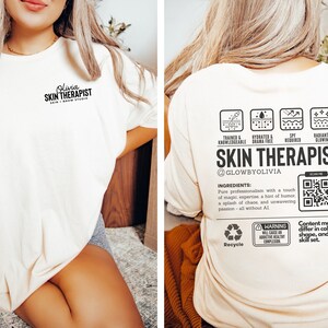May include: A white t-shirt with the text "Olivia SKIN THERAPIST" on the front and a detailed description of the services offered on the back. The back of the shirt also includes a QR code and the text "GLOWBYOLIVIA".