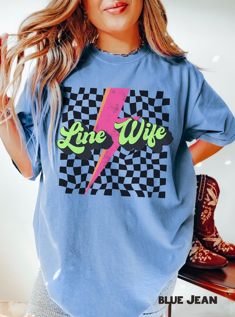 May include: A light blue t-shirt with a checkered pattern and a lightning bolt graphic. The text "Line Wife" is written in a retro font.