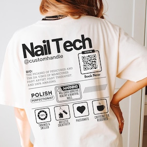 May include: White t-shirt with black text that reads "Nail Tech @customhandle". The shirt also features a QR code, the text "Scan Me", and the text "Book Now".