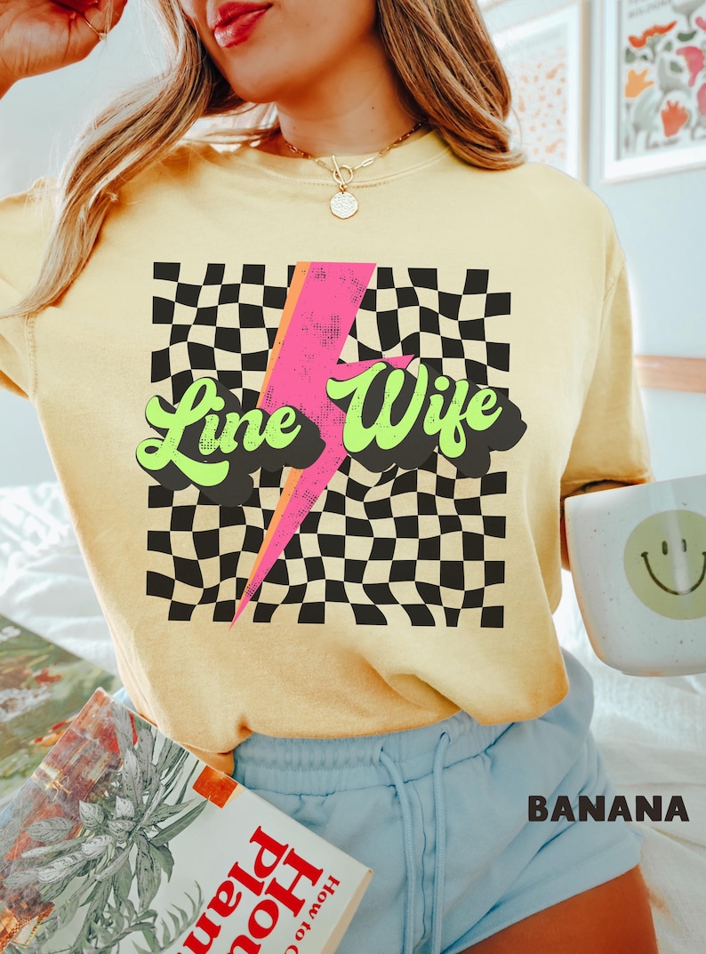 May include: A yellow t-shirt with a black and white checkered pattern, a pink lightning bolt, and the text "Line Wife" in green and yellow letters.