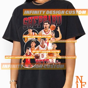 Puede incluir: Camiseta negra con un diseño de jugador de baloncesto. El diseño incluye el nombre "SHEPPARD" en rojo, imágenes del jugador y el texto "Young Boy". La camiseta tiene un aspecto vintage.