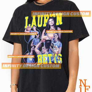 May include: Black t-shirt featuring a graphic of a woman holding a basketball, with the name "LAUREN" in yellow block letters. The word "BETTS" is also in yellow block letters. The shirt has a vintage look.