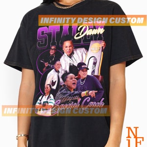 May include: Black t-shirt featuring a graphic of a woman with the text "STALEY Dawn Special Coach" in purple and white. The design includes the NCAA logo and multiple images of the woman. The shirt has a vintage, distressed look.