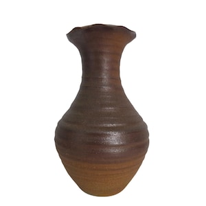May include: A brown ceramic vase with a bulbous body and a narrow, fluted neck. The surface features horizontal ridges throughout, with a darker brown tone on the upper section and a lighter, earthy brown hue on the lower base of the vessel.