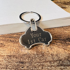 May include: Silver car-shaped keyring with a black background and the words "Your 1st Car" engraved in gold.