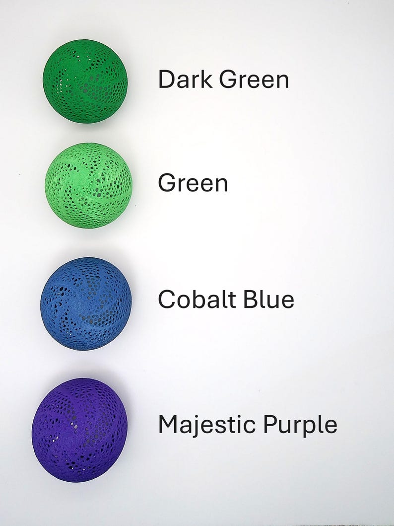 May include: Four decorative balls in different colors: dark green, green, cobalt blue, and majestic purple. Each ball has a lacy pattern.