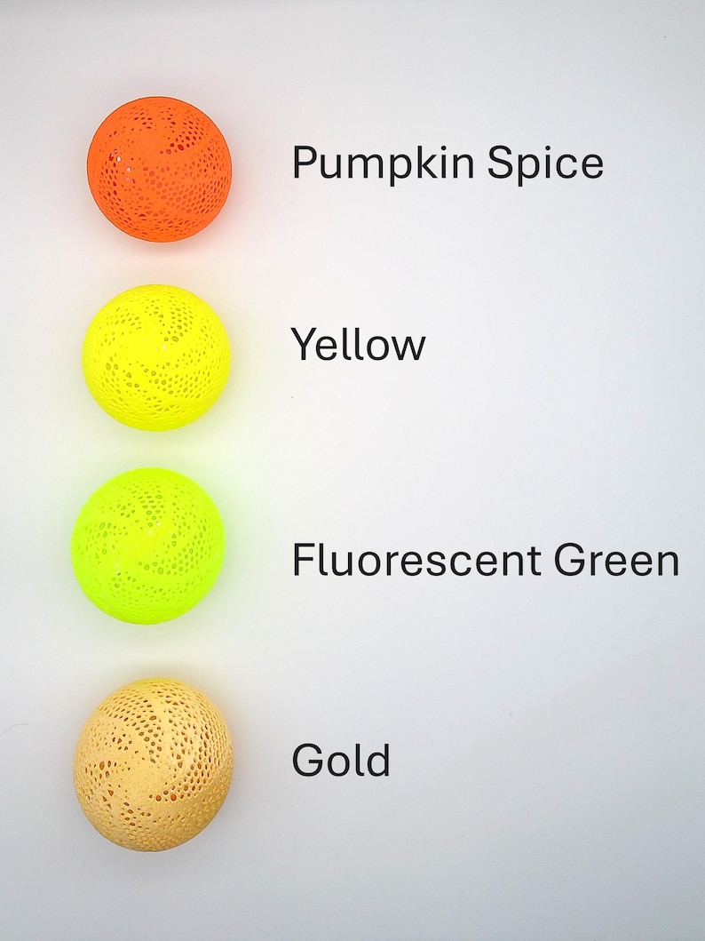 May include: Four decorative balls with a lacy pattern in different colors: pumpkin spice, yellow, fluorescent green, and gold.