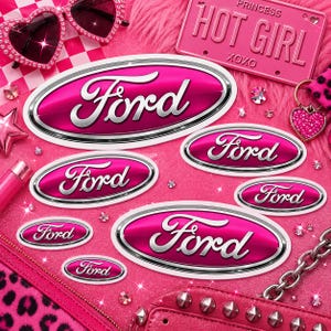 May include: A selection of pink Ford logo decals in different sizes, with a silver border, displayed on a pink, fluffy surface. The image includes heart-shaped sunglasses, a pink license plate that says "HOT GIRL", and other pink accessories.