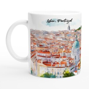 Könnte beinhalten: Weiße Keramiktasse mit einer Aquarell-Illustration von Lissabon, Portugal. Das Bild zeigt eine Stadtlandschaft mit roten Ziegeldächern und einem grünen Hügel im Hintergrund. Der Text "Lissabon, Portugal" ist in Schwarz auf die Tasse gedruckt.