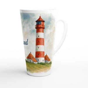 Könnte beinhalten: Weiße Keramik-Latte-Tasse mit einer Aquarell-Illustration eines rot-weiß gestreiften Leuchtturms und zwei kleinen Gebäuden. Die Tasse hat einen gebogenen Griff und das Wort "and" ist auf der Seite geschrieben.