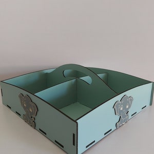 May include: A light blue wooden storage box with a handle and four compartments. The box has two small elephant designs on the front and sides.