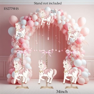 May include: Pink and white balloon arch with three white carousel horse centerpieces, each with a pink saddle and a gold base. The centerpieces are 34 inches tall and the arch is 1 foot tall. The text "ES2779HS" and "Stand not included" are visible in the image.