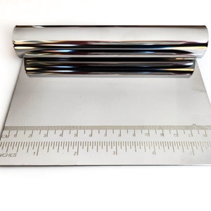 May include: A silver metal pastry scraper with a ruler marked in inches and centimeters. The scraper is rolled up and the ruler is visible.