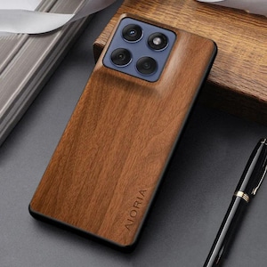 May include: A rectangular smartphone case featuring a brown wood grain finish and a black camera module with four circular lenses. The brand name AIORIA is embossed in the lower section of the wood panel, which is set against a dark surface.