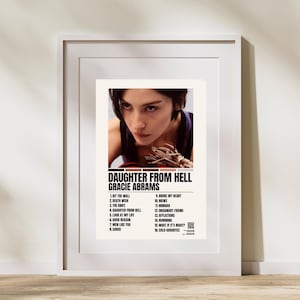 Op de afbeelding: Een ingelijste poster met een portret van een persoon met kort donker haar, een kleurenpaletbalk en de tekst Daughter From Hell door Gracie Abrams. De tracklist bevat 16 nummers variërend van Hit The Wall tot Cold Goodbyes in zwarte letters.