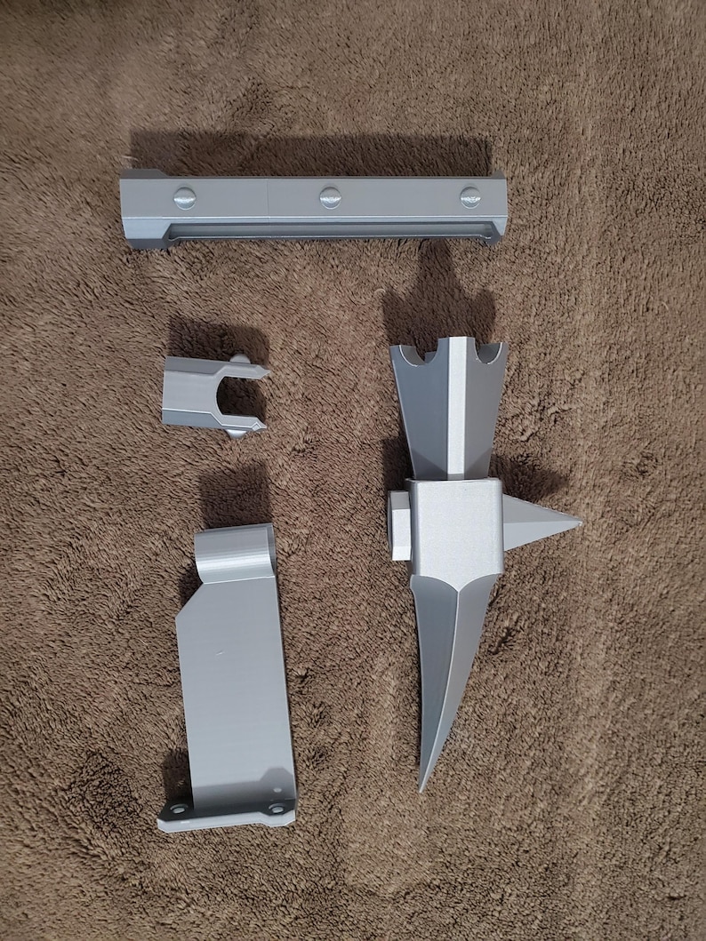 May include: A collection of gray 3D-printed parts, including a long rectangular piece with rounded screw heads, a small U-shaped piece, a flat piece with a right-angle bend, and a complex, pointed tool.