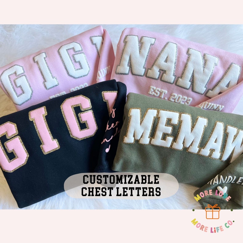 May include: Four sweatshirts with customizable chest letters. The sweatshirts are in pink, black, green, and pink. The letters are in white, pink, and gold. The text on the sweatshirts reads "Gigi", "Nana", "Gig", and "Memaw". The text on the pink sweatshirt reads "Est. 2023".