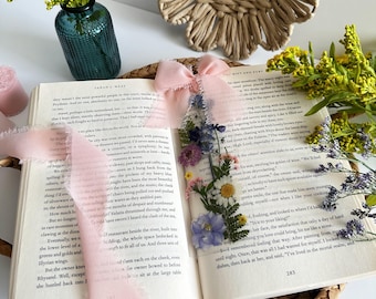 Könnte beinhalten: Ein offenes Buch mit einem rosa Schleifen-Lesezeichen und gepressten Blumen. Das Buch ist auf einer Seite mit Text über ein Restaurant und einer Beschreibung des Essens geöffnet.