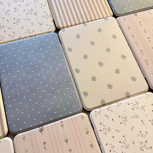 Puede incluir: Una colección de bandejas decorativas rectangulares con esquinas redondeadas. Las bandejas presentan varios diseños, incluyendo florales, lunares, rayas y hojas. Los colores incluyen azul claro, rosa, beige y blanco. Las bandejas están dispuestas juntas.