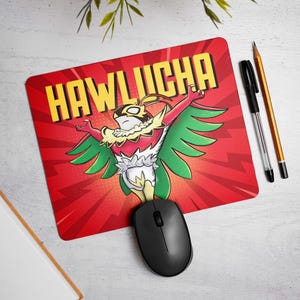 May include: Red mousepad with the word "HAWLUCHA" in yellow block letters. The mousepad features a cartoon character with red, green, yellow, and white colors. A black computer mouse is on the mousepad.
