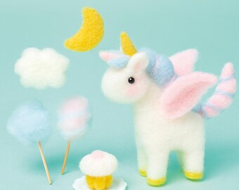 May include: A whimsical felt unicorn with pink wings, a blue and pink mane, and a yellow horn. Accompanying the unicorn are felt clouds, a yellow crescent moon, cotton candy on sticks, and a cupcake on a white plate. The scene is set against a light blue background.