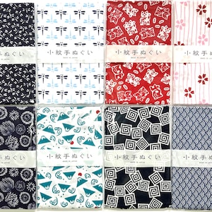 May include: Eight rectangular fabric cloths with various patterns including dragonflies, cats, cherry blossoms, fireworks, mountains, waves, and geometric shapes. Each cloth features a white paper band with the Japanese text 小紋手ぬぐい and MADE IN JAPAN.