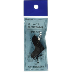 Puede incluir: Un dedal de cuero negro con un anillo de metal. El dedal está empaquetado en una bolsa de plástico azul con el texto "Olympus オリムパス 皿付皮指ぬき 使用方法" impreso en él.