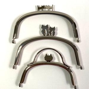 May include: Three silver metal purse frames with cat silhouettes. The largest frame has three cats, the middle frame has two cats, and the smallest frame has one cat.