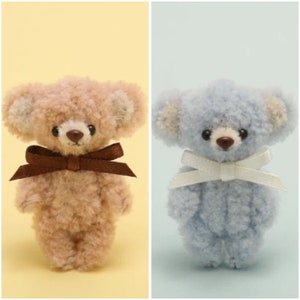 May include: Two small plush teddy bears, one is light brown with a brown bow and the other is light blue with a white bow.