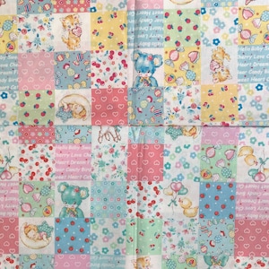 May include: A patchwork fabric with a repeating pattern of pastel coloured squares featuring teddy bears, kittens, and candy. The fabric has a white background with pink, blue, green, and yellow squares. The text "Hello Baby Sweet Cherry Love" is repeated throughout the fabric.