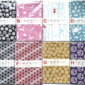 May include: Eight rectangular tenugui cloths arranged in two rows, each wrapped in plastic with a paper band labeled A through H. The patterns include white motifs on black, pink, blue, and purple backgrounds, featuring umbrellas, rabbits, fish, and flowers.