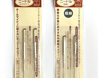 May include: Two Hamanaka brand needle felting tool sets in clear plastic packaging. The left package contains two regular needles, model H441-014. The right package contains two extra-fine needles, model H441-023. Both feature brown and cream labels.