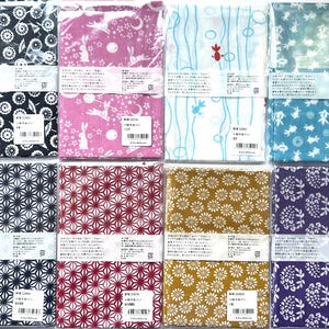 May include: Eight rectangular fabric cloths in individual clear plastic packaging, each featuring distinct patterns including geometric shapes, floral motifs, rabbits, and fish in various colors like navy, pink, white, blue, red, gold, and purple.