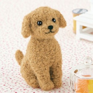 Puede incluir: Un juguete de peluche de caniche marrón y blanco con ojos negros y nariz negra. El juguete está sentado sobre un fondo blanco con flores rosas.